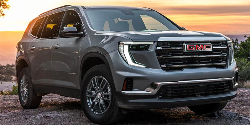 A grey 2025 FMC Acadia parked with the sunset in the backround.