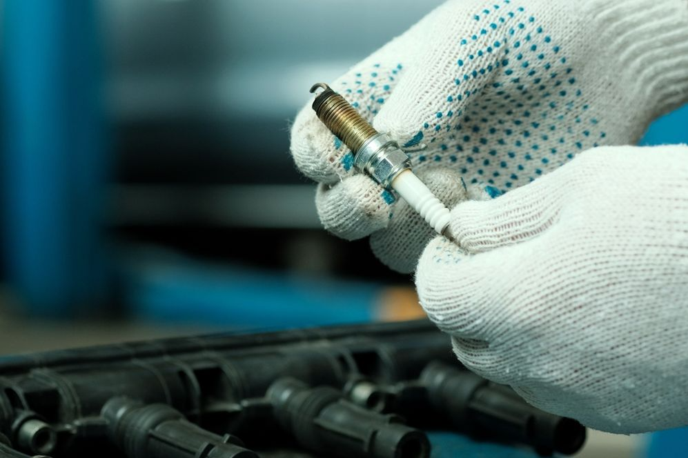 A photo of a mechanic holding a spark plug.