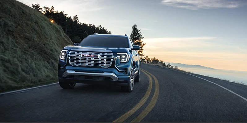 A dark blue 2026 GMC Terrain driving down the road.