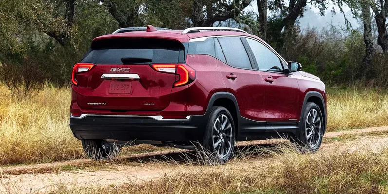 A photo of a red 2024 GMC Terrain driving down the road.