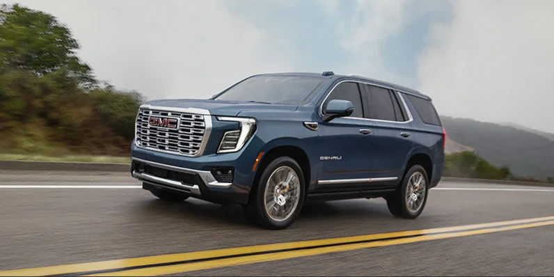 A photo of a 2026 GMC Acadia driving down the road.