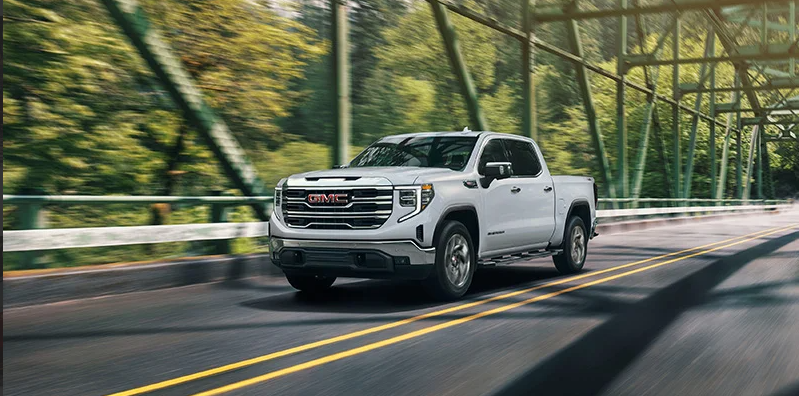A white 2026 GMC Sierra 1500 driving across a bridge.